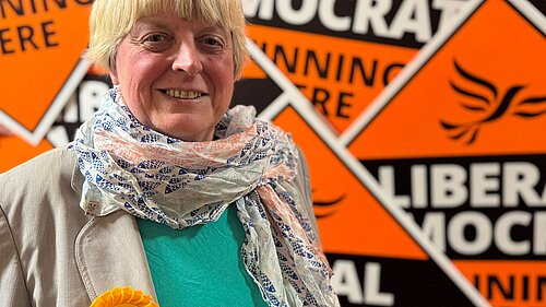 Liberal Democrat Candidate Jackie Pearcey in front of a sea of Lib Dem diamonds